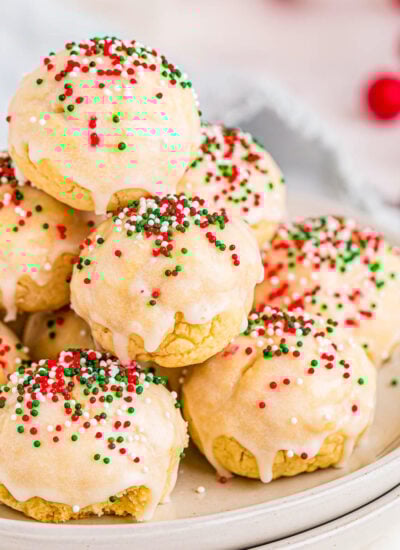 italian christmas cookies decorated with red, green and white nonpareils sitting on two white round plates.