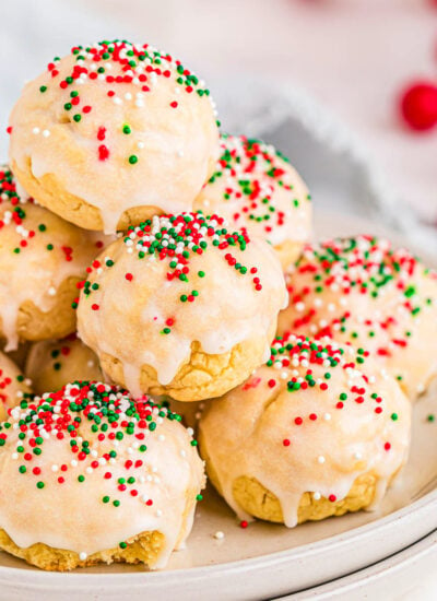 italian christmas cookies decorated with red, green and white nonpareils sitting on two white round plates.