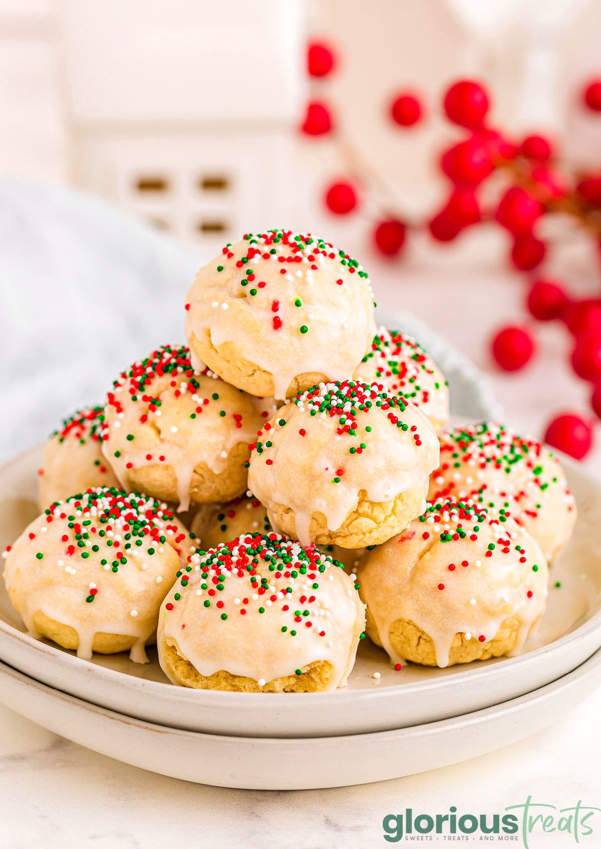 italian christmas cookies decorated with red, green and white nonpareils sitting on two white round plates.