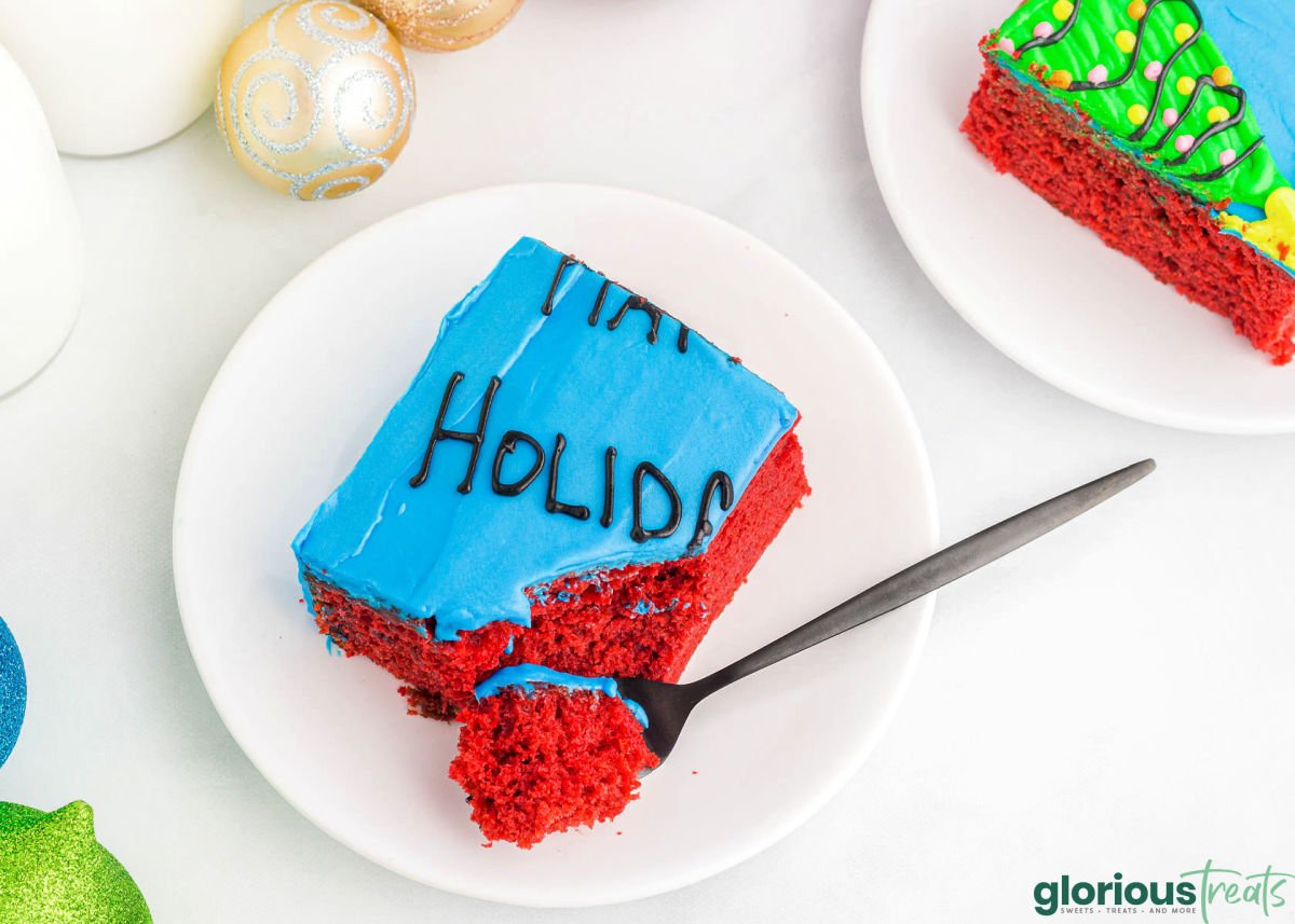 slice of red velvet cake and decorated to look like an ugly christmas sweater. fork has cut off one edge of the piece of cake on a round white plate.