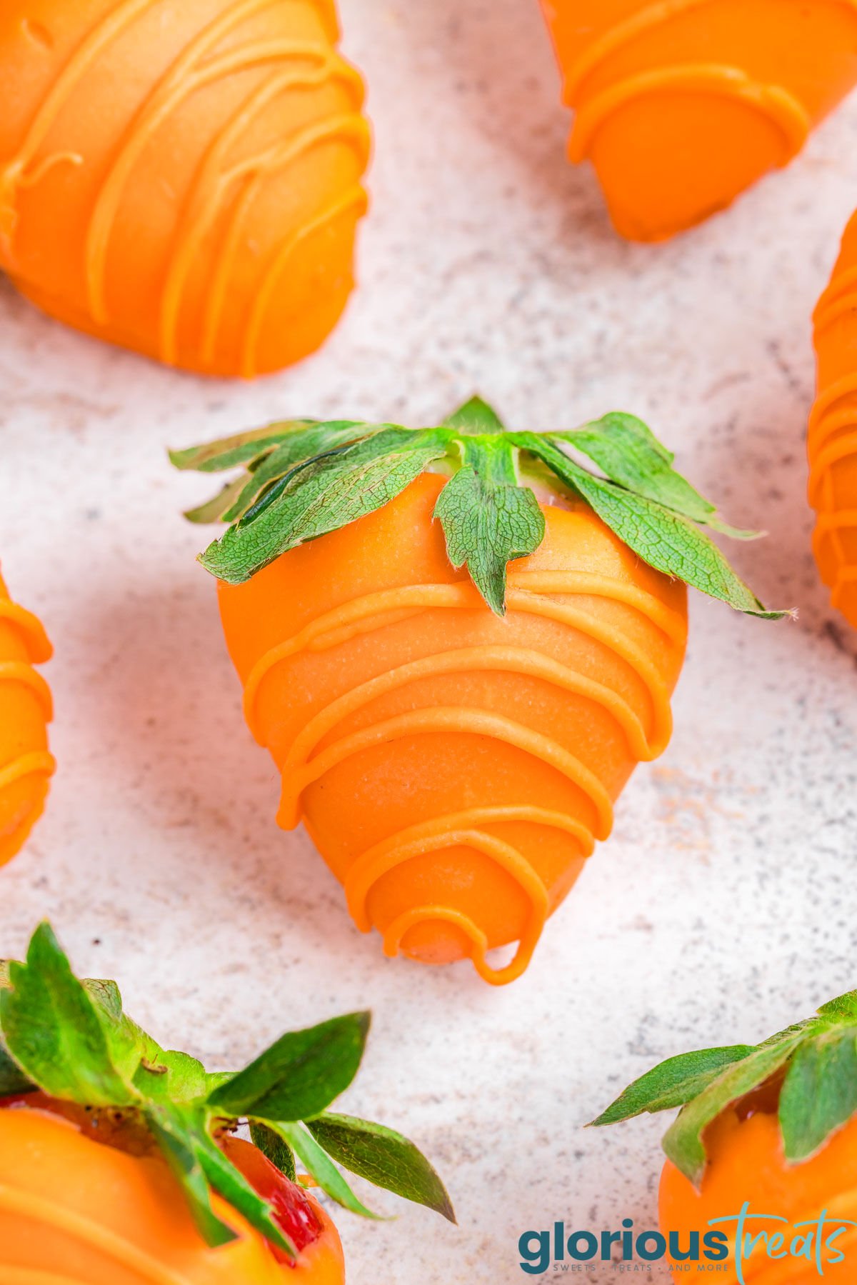 close up of strawberries dipping in orange candy to look like carrots.