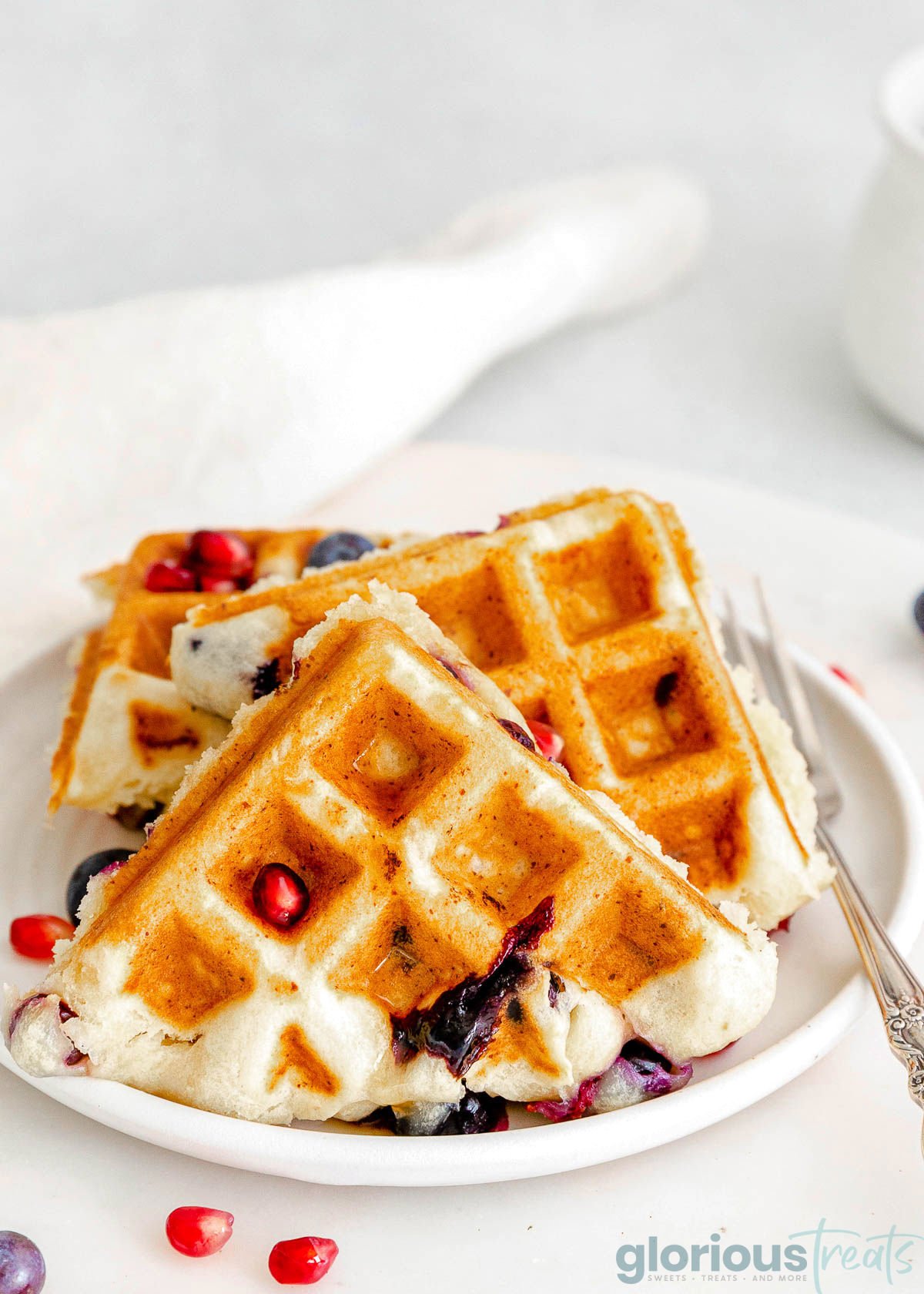 white round plate topped with three waffles made with ricotta cheese and blueberries.