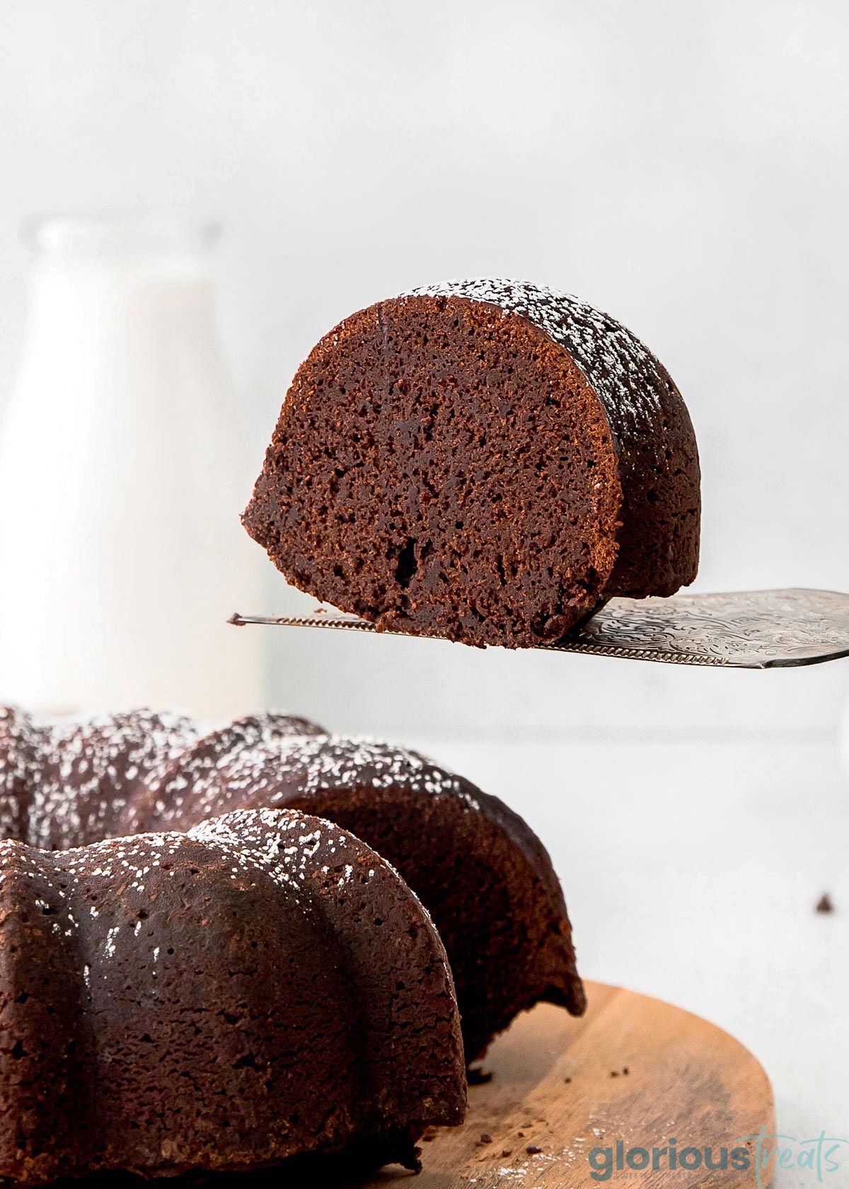 A piece of chocolate bundt cake being lifted away from the rest of the cake.