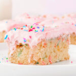 A slice of funfetti sheet cake on a white plate.