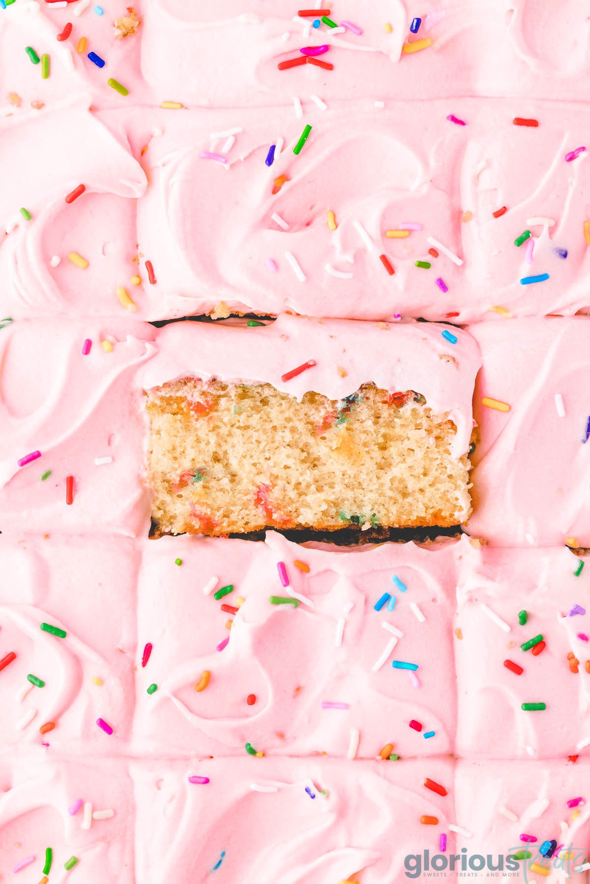 A top down view of funfetti sheet cake with a slice tilted up.