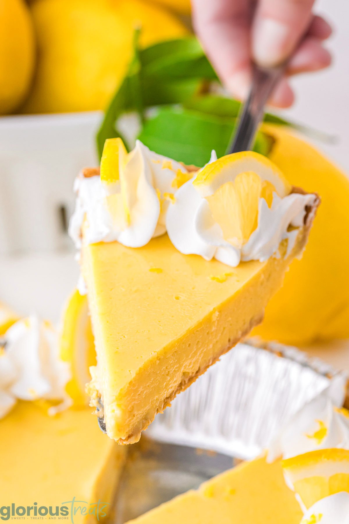 A metal pie serve holding a slice of lemon pie over the rest of the pie.