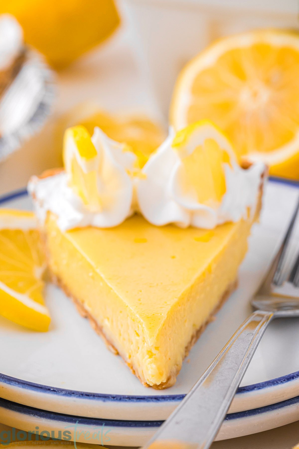 A slice of lemon pie on a stack of white plates.