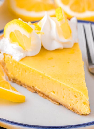 A slice of lemon pie on a stack of white plates.