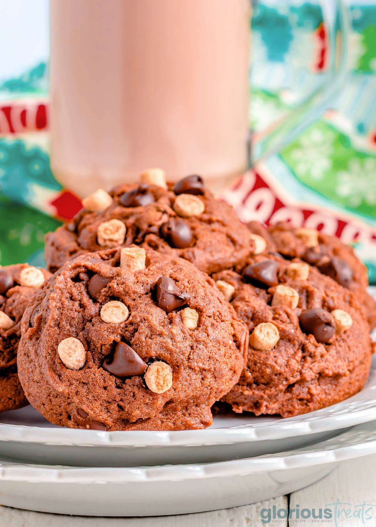 Hot Chocolate Cookies on a white plate with a glass of chocolate milk and a festive linen in the background.