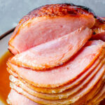 Apple cider ham glaze recipe on spiral sliced ham on platter.