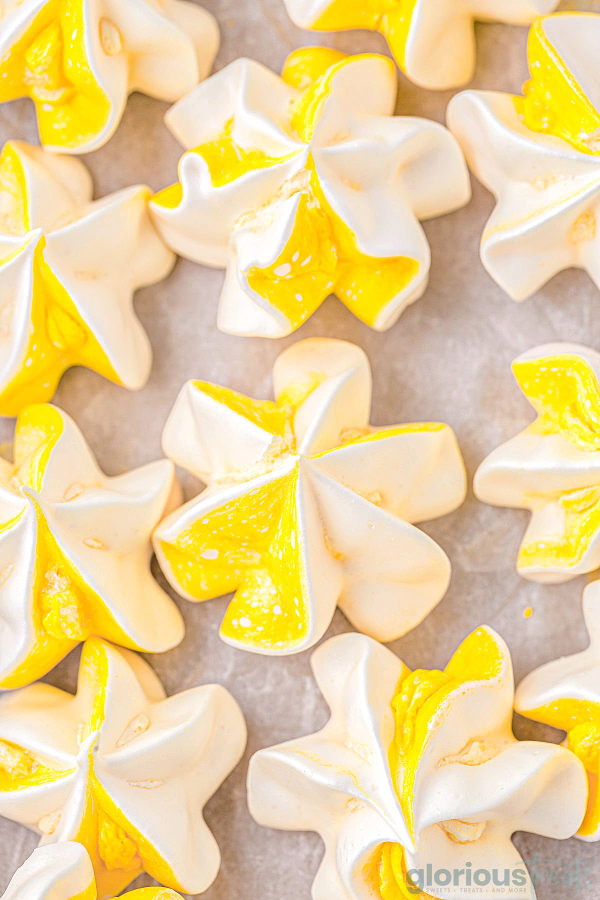 A close up view of lemon meringue cookies on a parchment lined baking sheet.