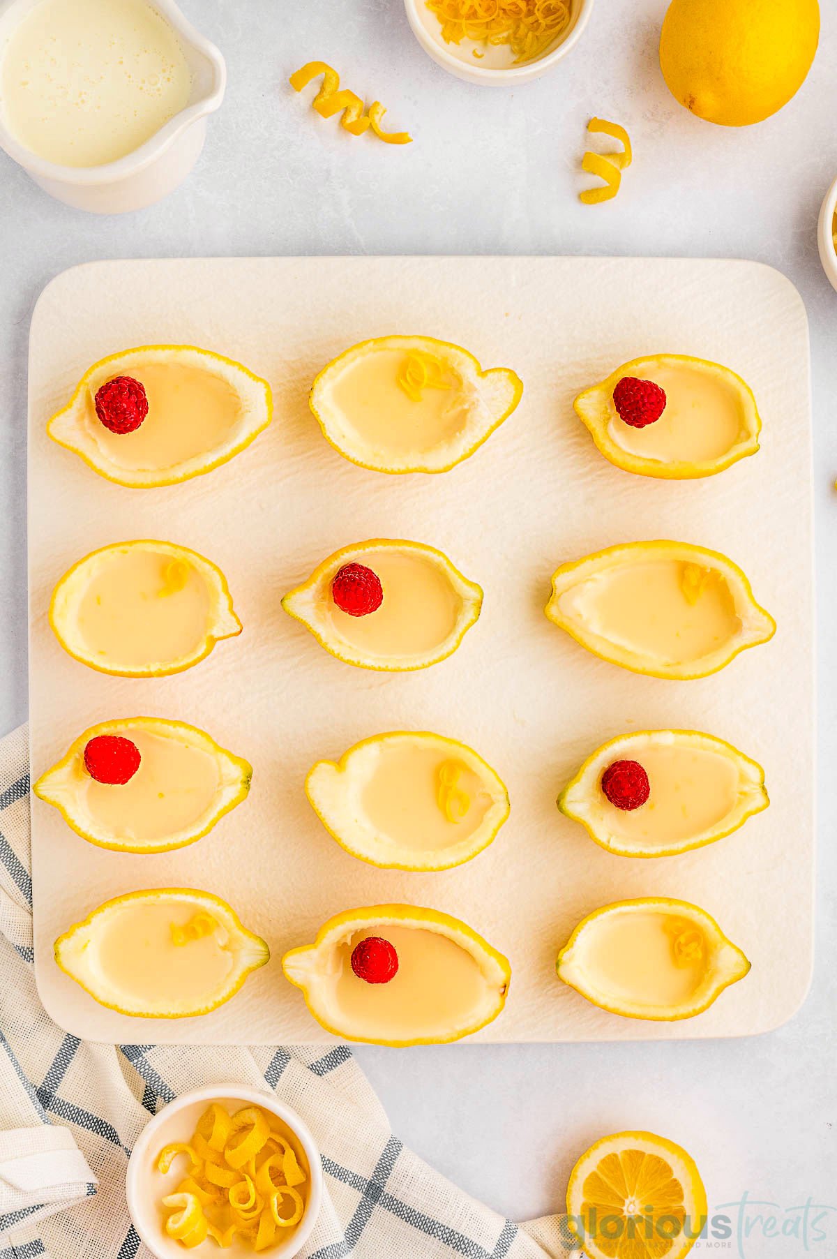 A top down view of lemon posset in lemon halves. Toppings are scattered around the posset.