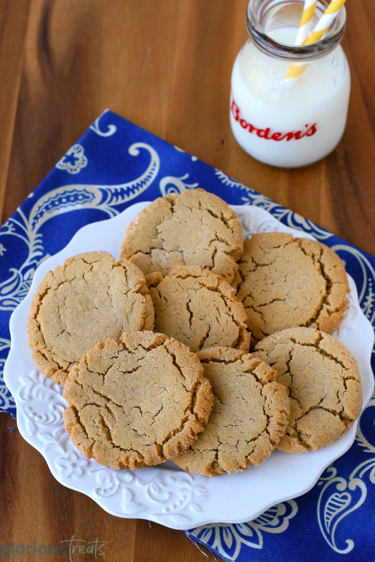 Overhead slightly angled view of white round plate filled with soft and chewy peanut butter cookies next to a jug of milk.