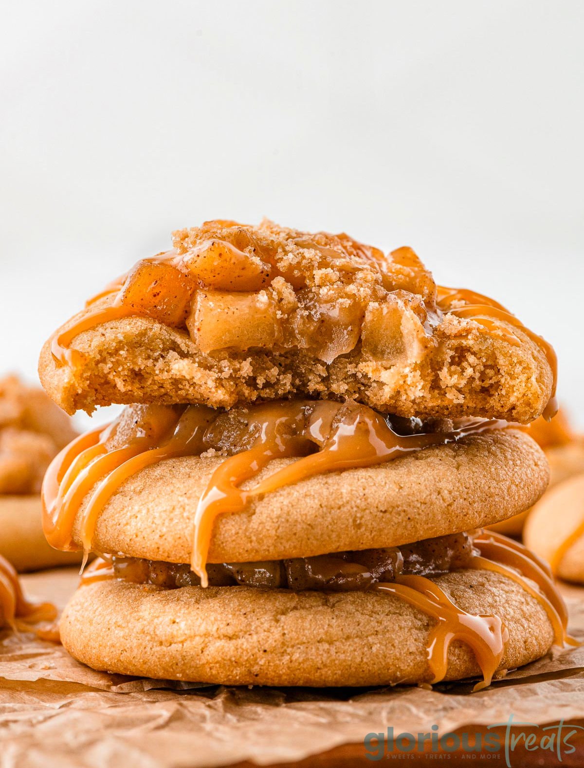 Three caramel apple cookies stacked with the top cookie bitten in half.