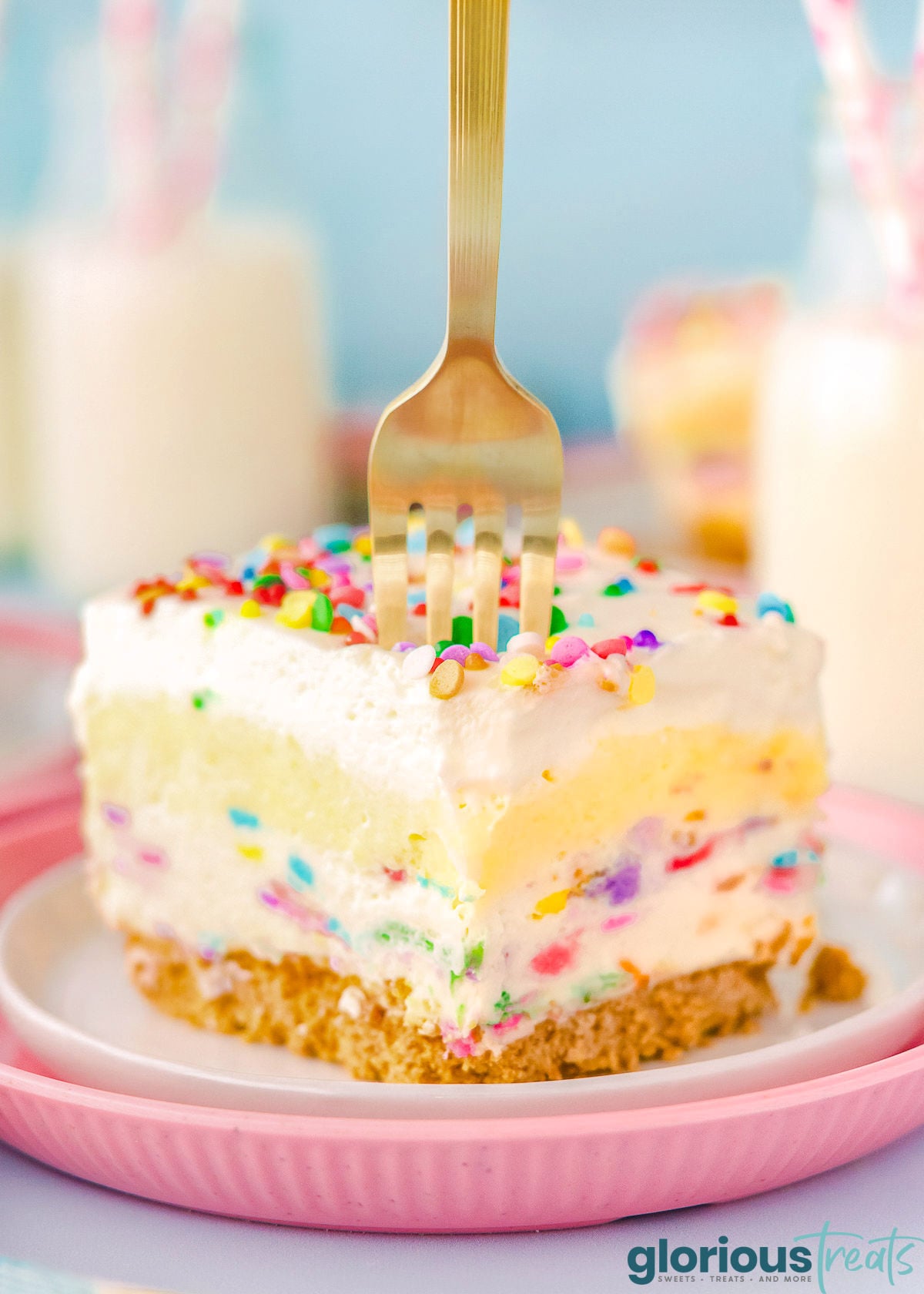 Funfetti Lush layered dessert sitting on white and pink plate with fork sticking out the top.