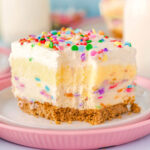 Funfetti Lush layered dessert sitting on white and pink plate with fork lines showing where a bite was removed.