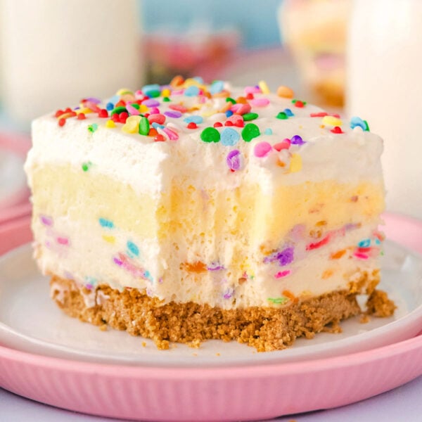 Funfetti Lush layered dessert sitting on white and pink plate with fork lines showing where a bite was removed.