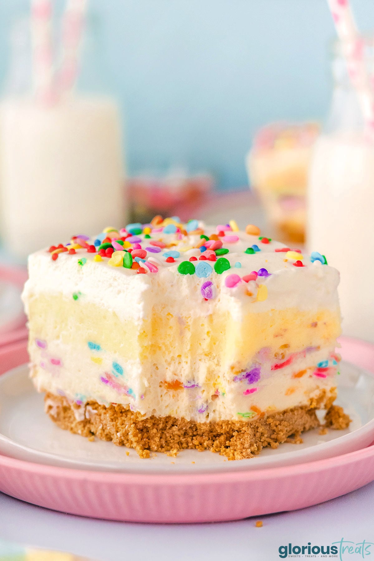 Funfetti Lush layered dessert sitting on white and pink plate with fork lines showing where a bite was removed.