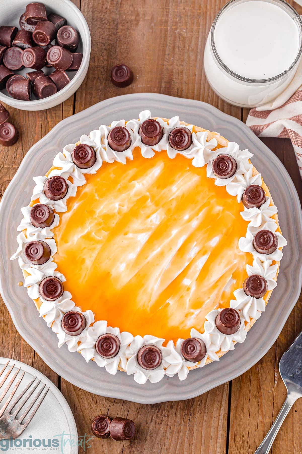 Overhead shot of chocolate caramel cheesecake decorated with caramel sauce, whipped cream and Rolo candy.