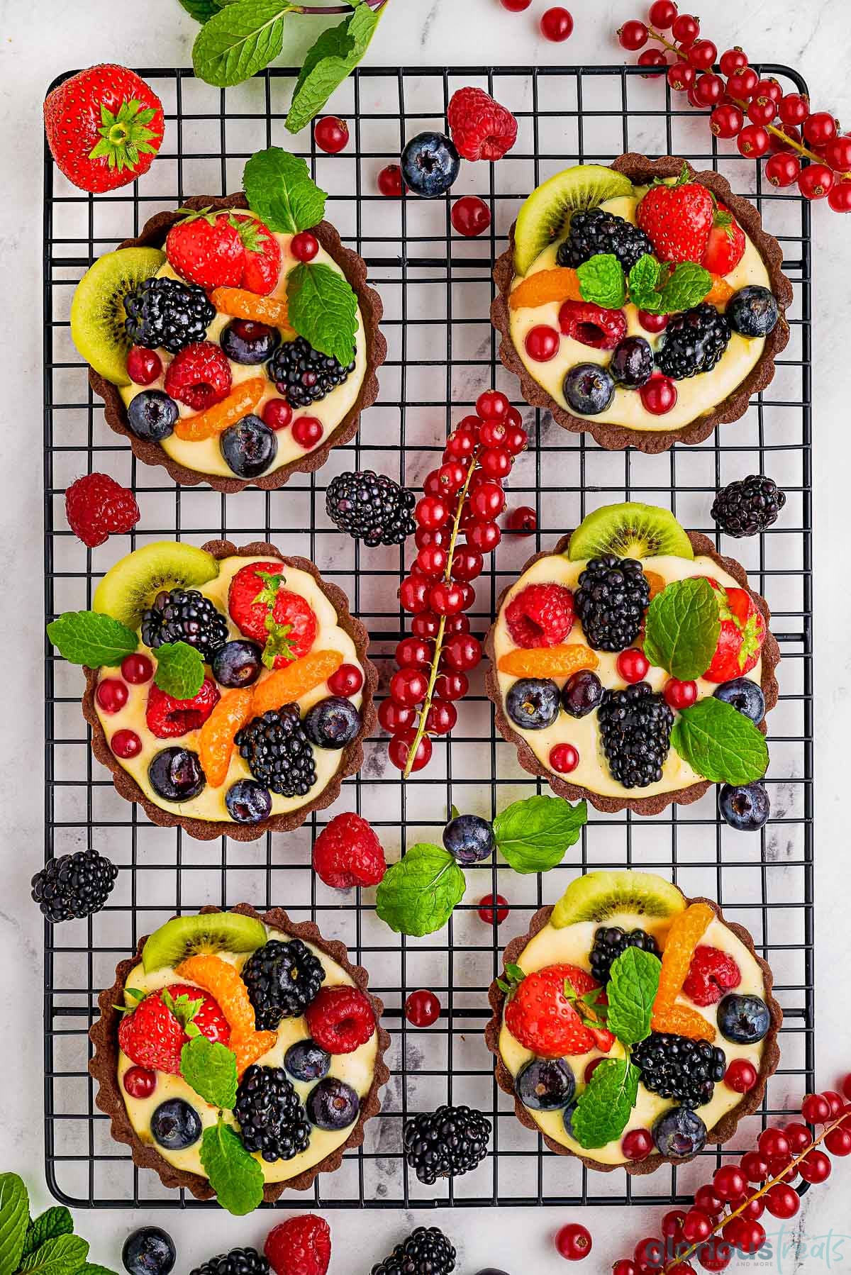 Overhead shot of six tartlets on black cooling rack.